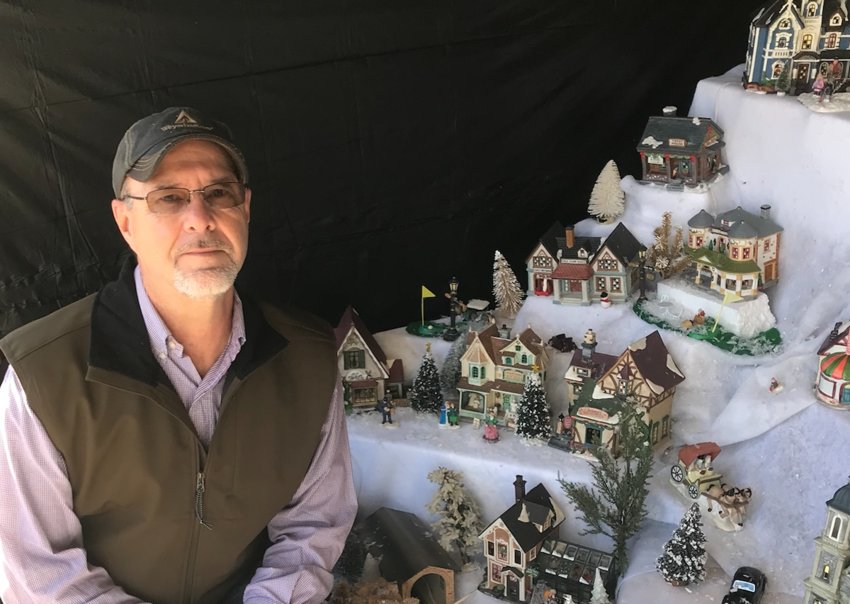 Keith May kneels next to the miniature Christmas Village he assembled next to the Justice Court bulding across from the Courthouse. The window display features over 200 buildings and scenes including the Neshoba County Fair through Christmas.